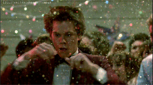 short clip of Kevin Bacon dancing and spinning with glitter falling from the ceiling