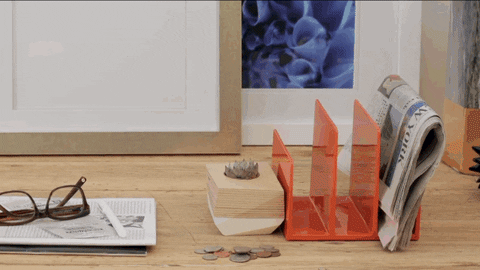 A GIF of a desk slowly being organized. In stop-motion fashion, mail is sorted, and notebooks and receipts are put into their respective boxes and drawers. 